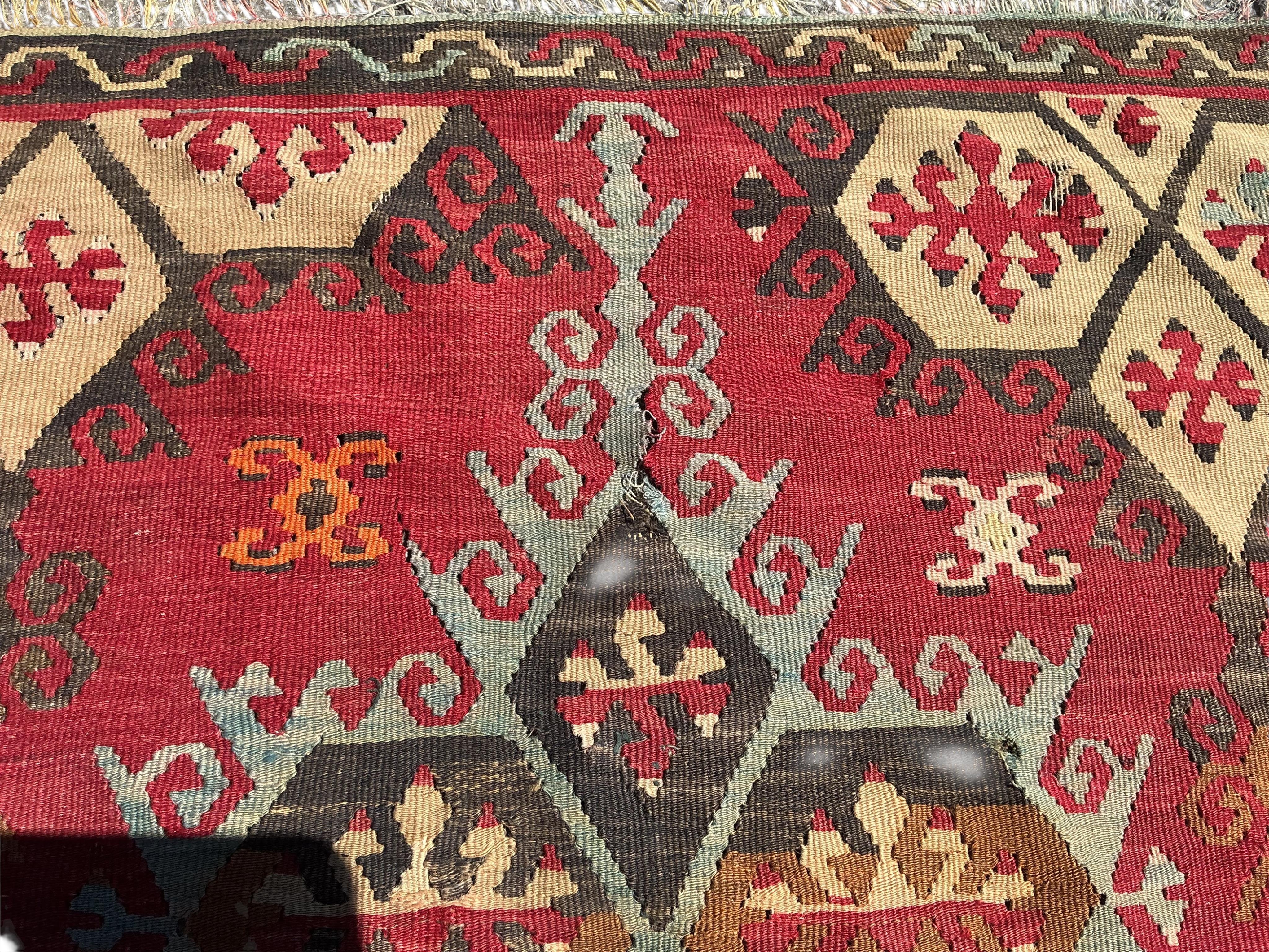 A Turkish Anatolian Kilim polychrome flatweave carpet, woven with geometric lozenges, on a pink field, 350 x 273cm